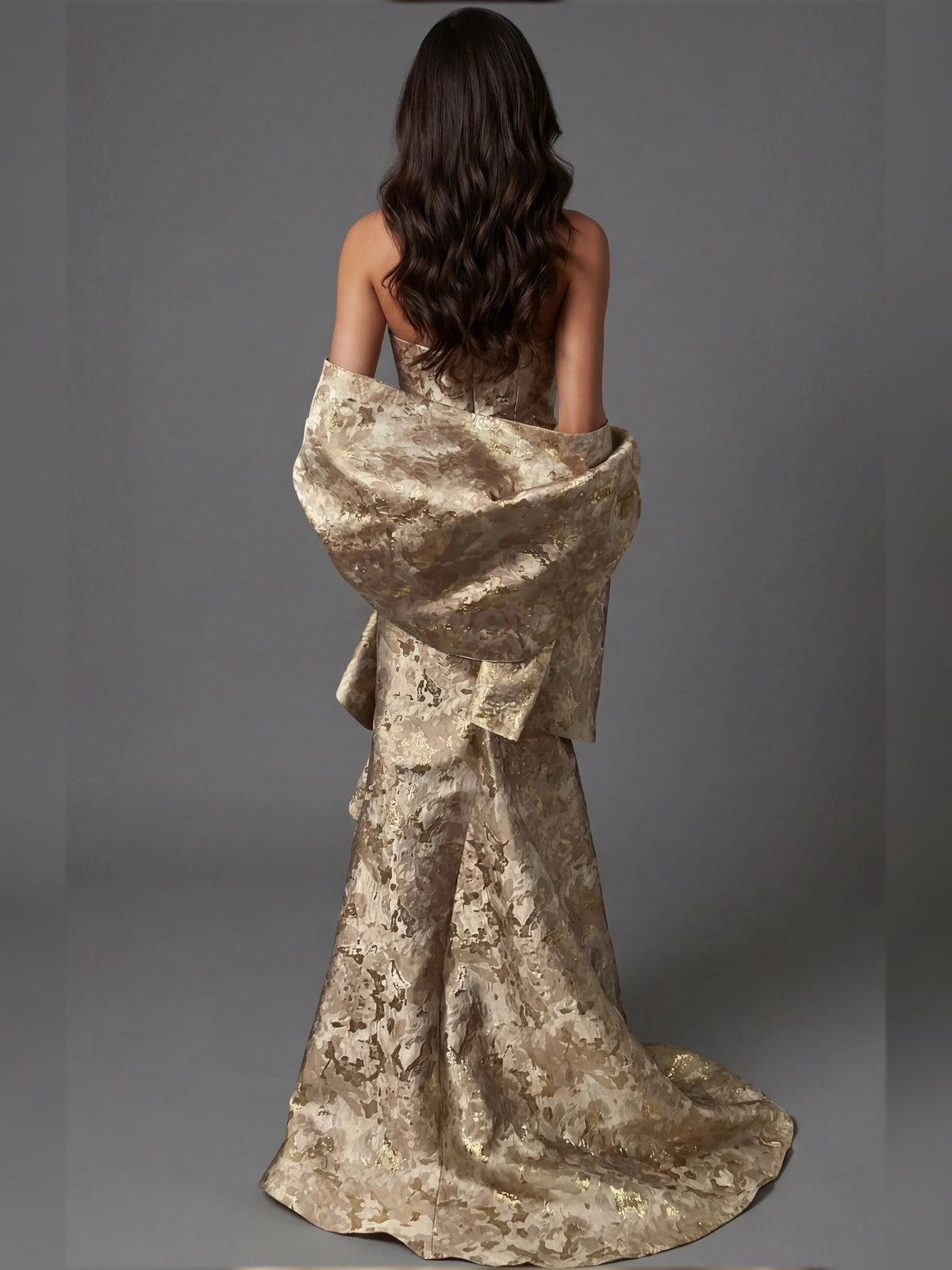 Back of strapless mermaid formal dress in metallic gold with draped ruffles, floor-length.