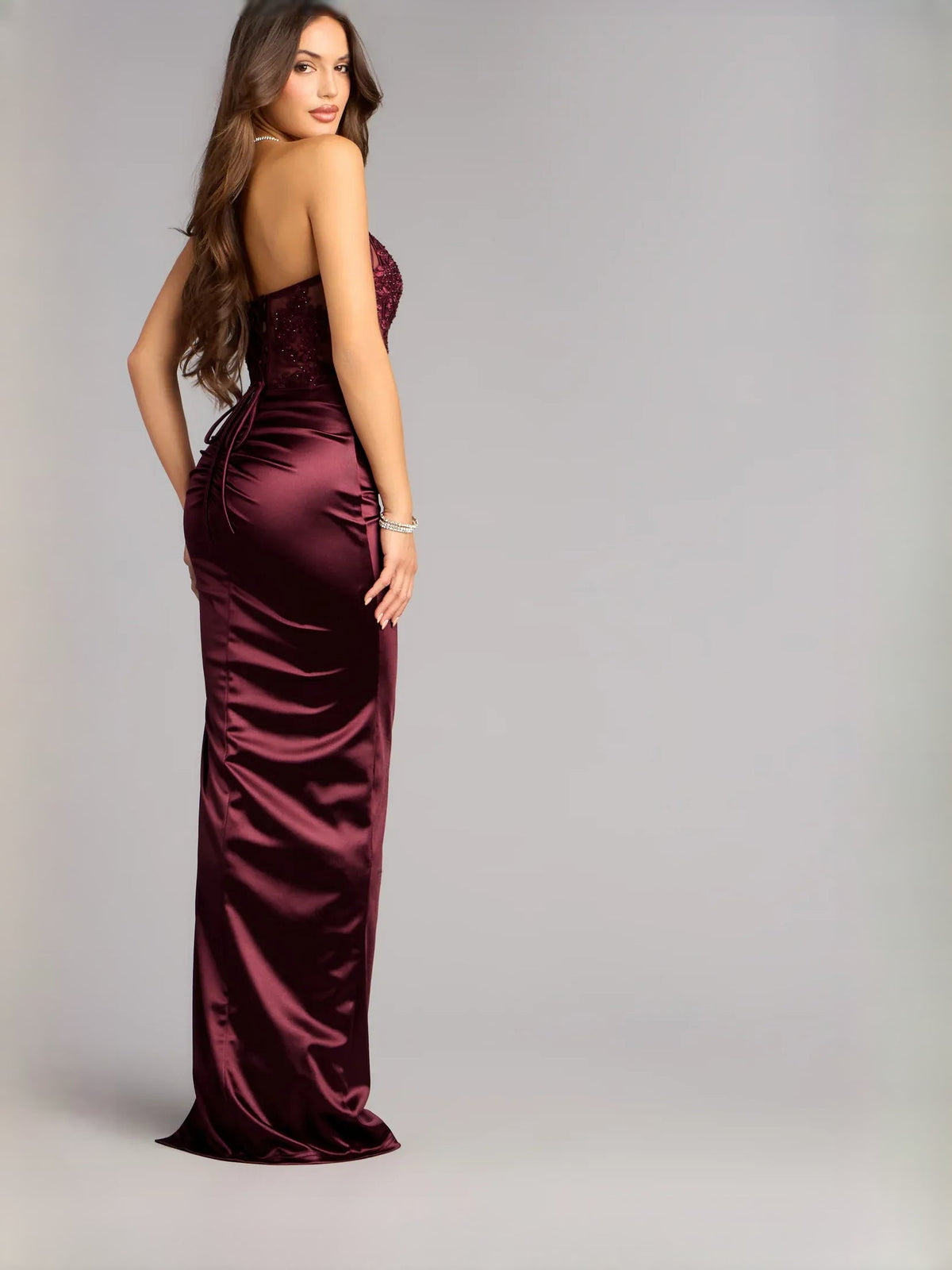 Wine strapless satin formal dress in column style with front thigh slit, side view.