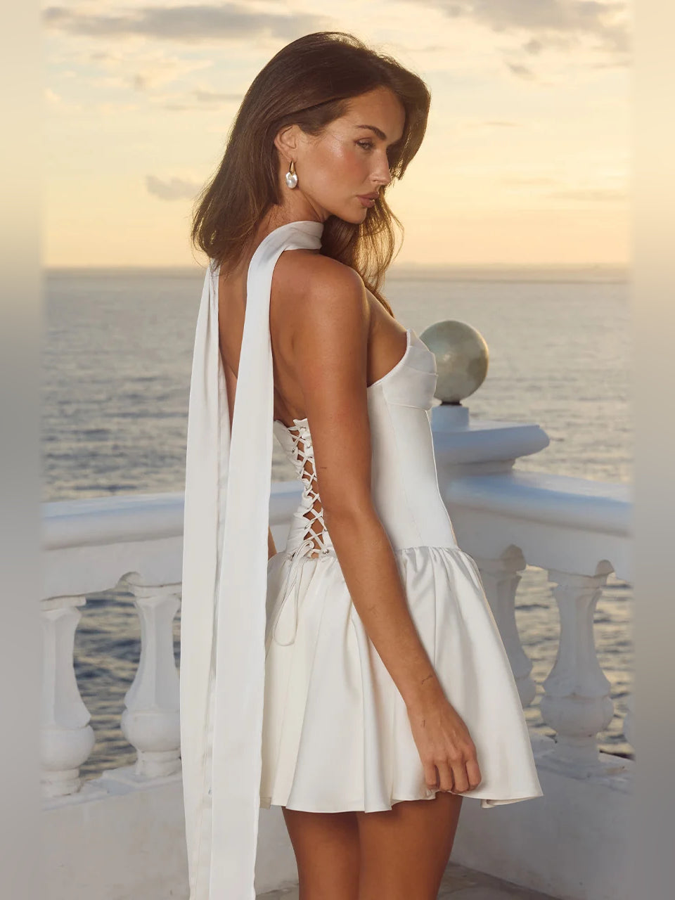 Ivory strapless mini dress with high halter neckline and pleated flared skirt, side view