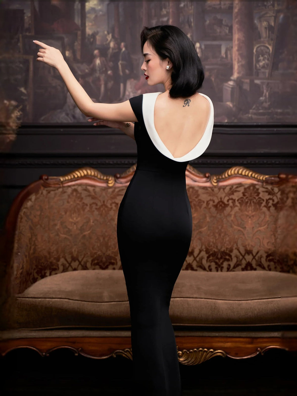Black mermaid maxi dress with white-trimmed open back and fitted waist