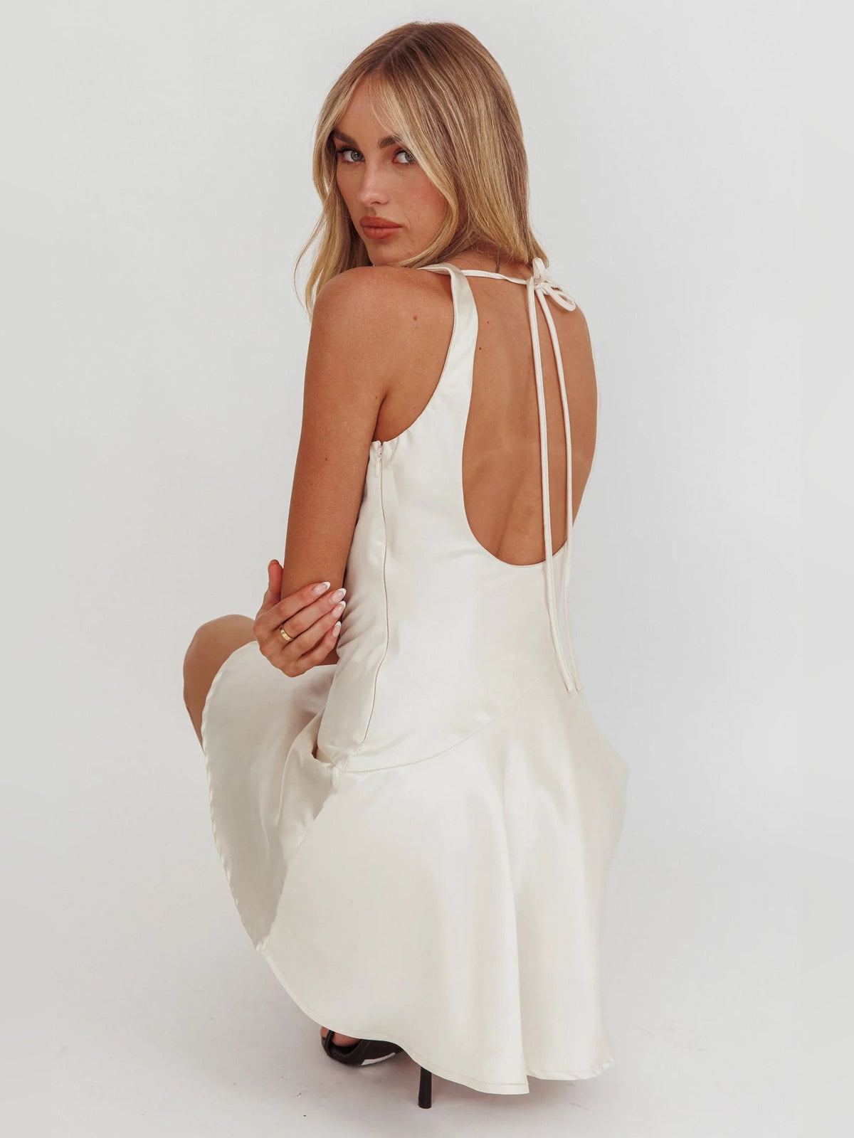 Ivory cowl-neck mini dress with open back and thin tie straps; skater skirt.