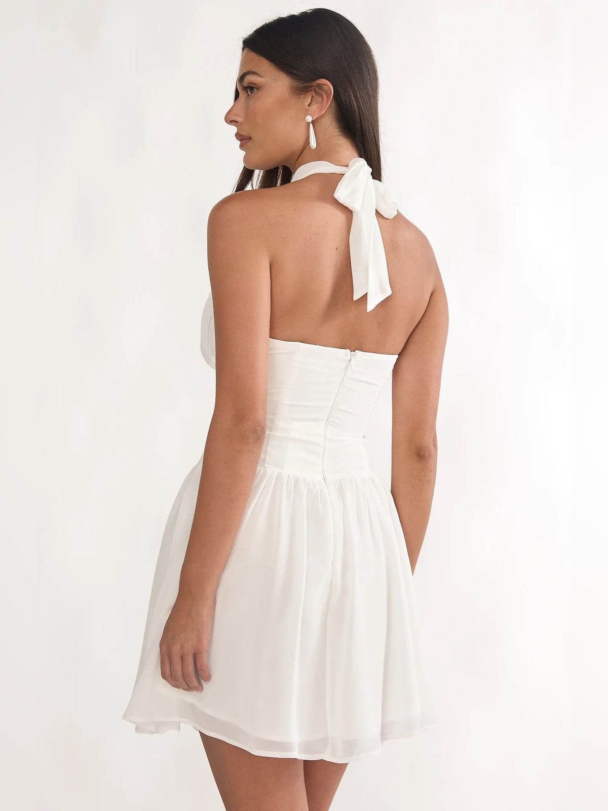 White halter mini dress with open back and tie detail, pleated tiered skirt