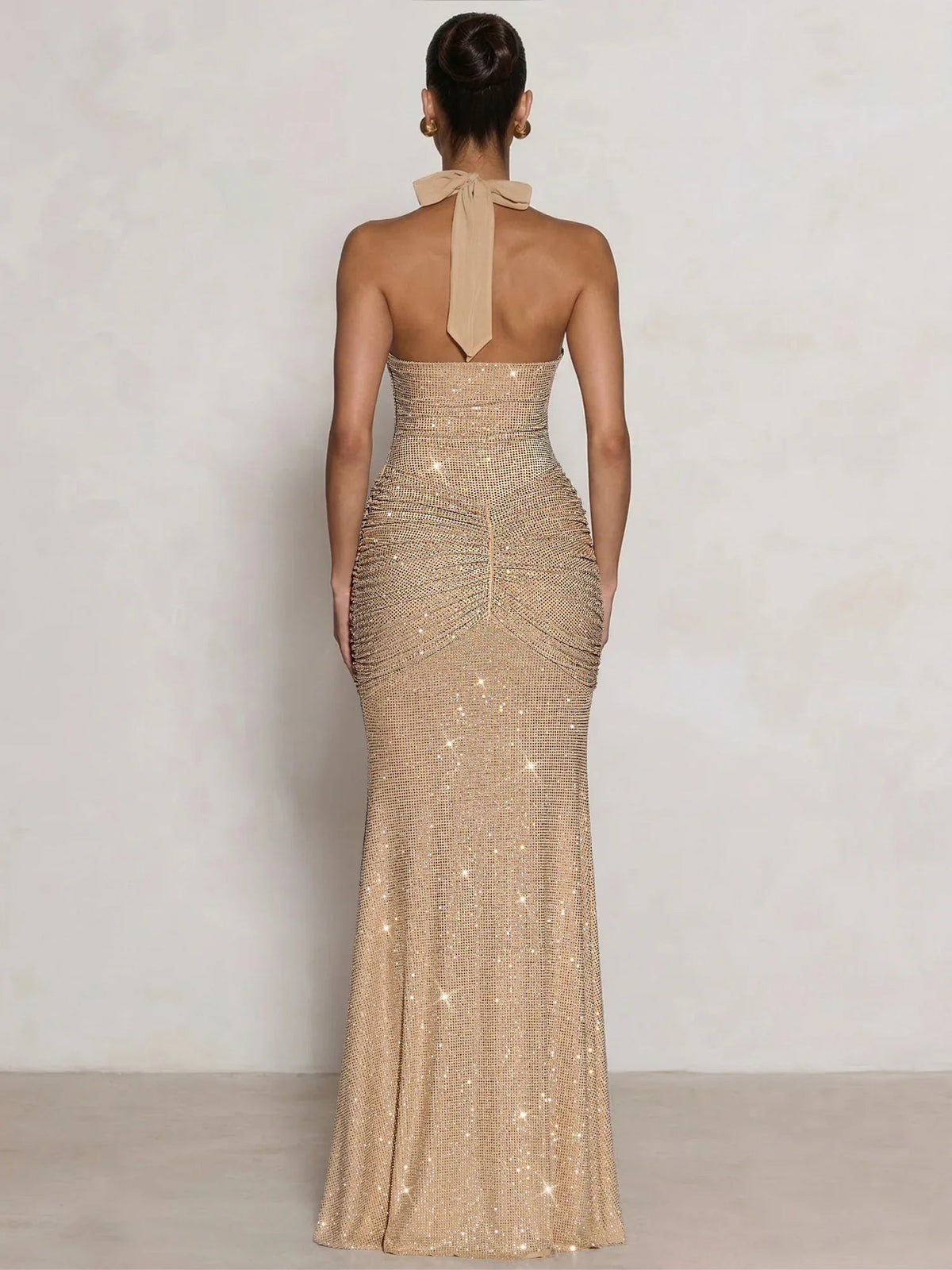 Back view: gold halter neck ruching midi formal dress with sequined finish