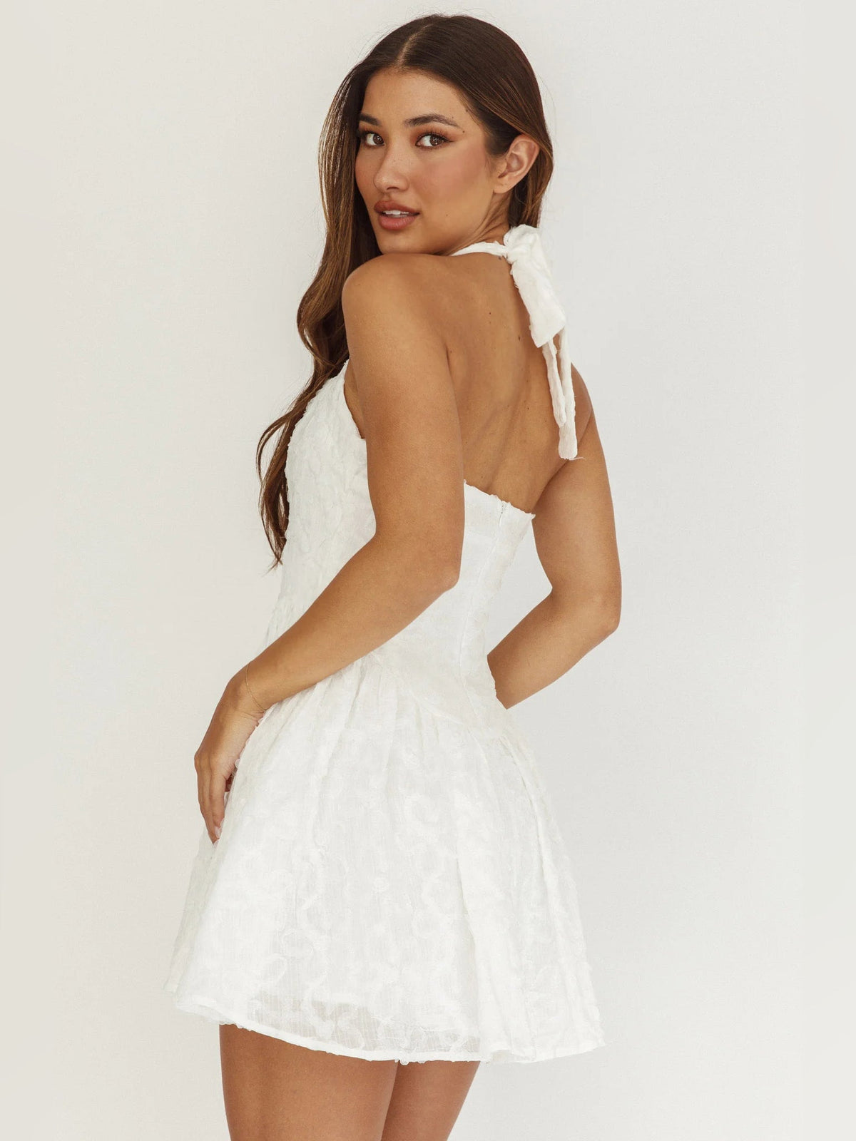 White halter neck mini homecoming dress with square neckline, bow detail, flared tiered skirt