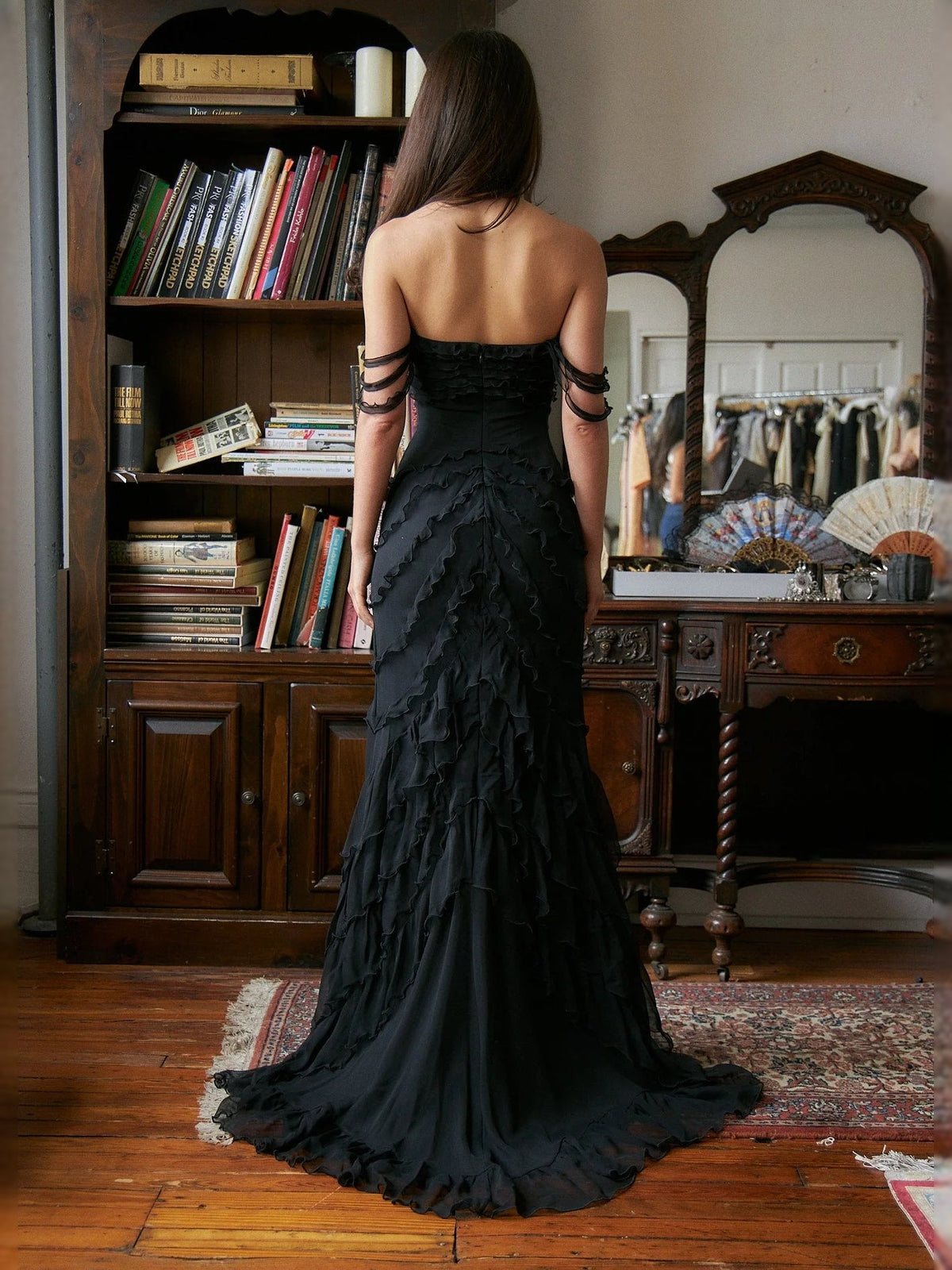 Back view of black strapless mermaid prom dress with layered ruffles, full length
