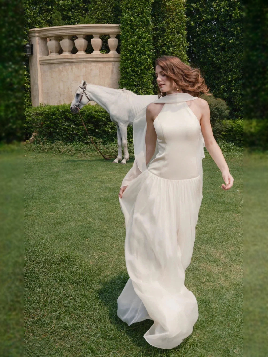 Ivory chiffon halter A-line gown with open back and flowing drape over shoulders