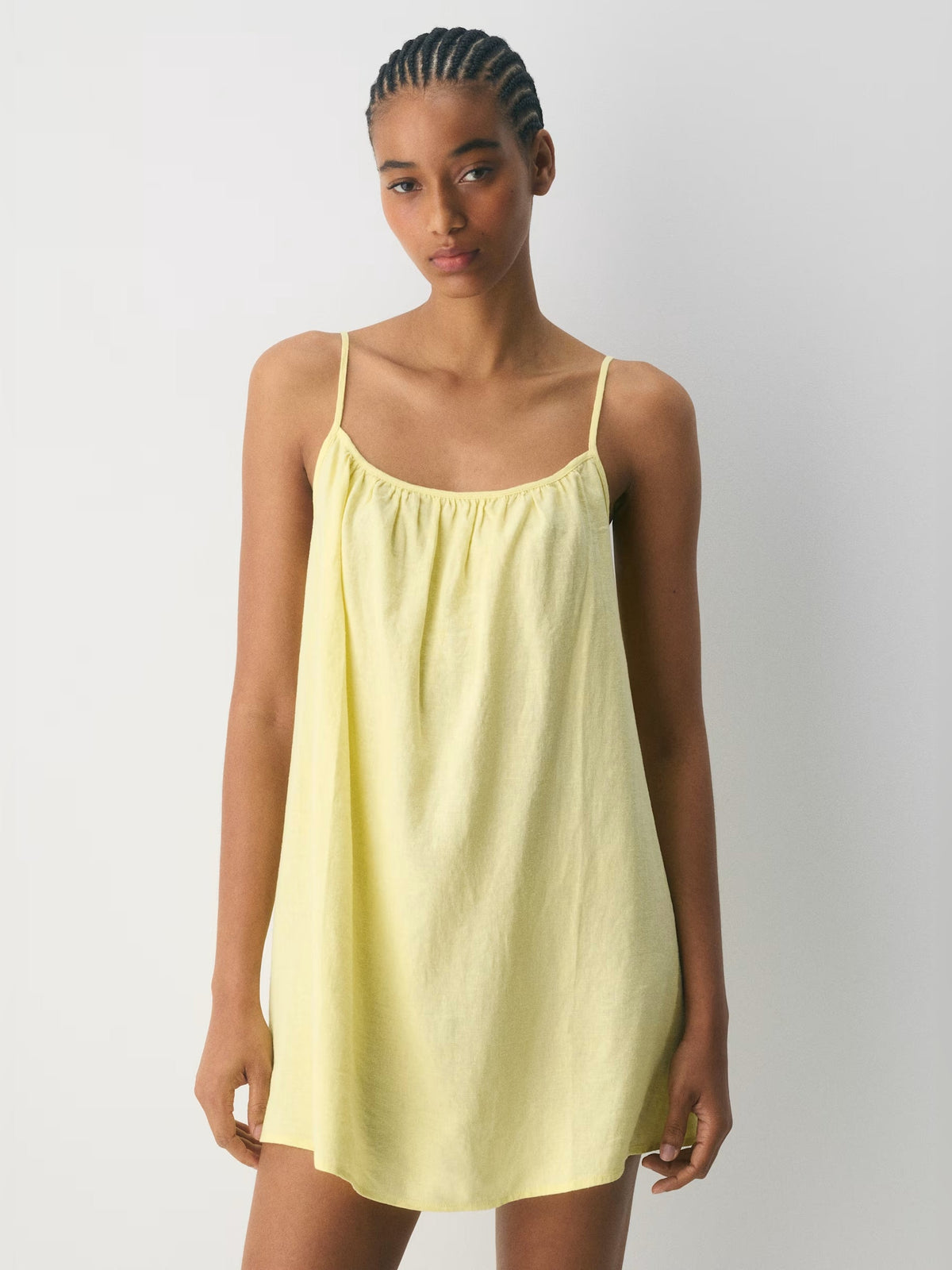 Light yellow sleeveless mini dress with thin spaghetti straps and gathered bodice