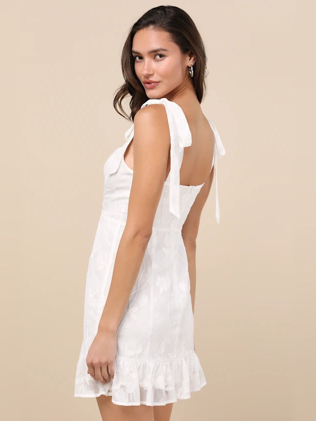 White embroidered floral mini dress with bow shoulder straps, side view, ruffled hem