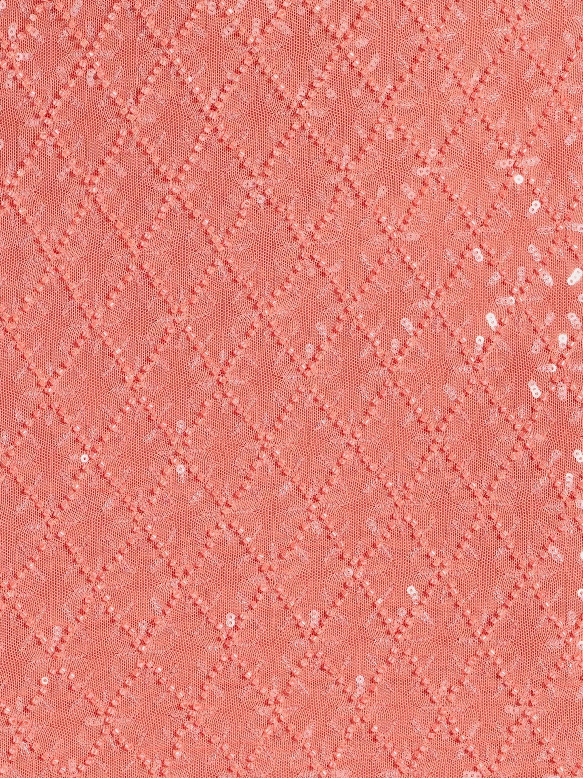 Close-up of coral pink sequin fabric with diamond pattern texture