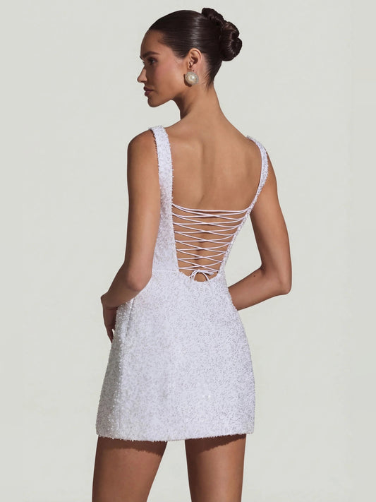 White mini dress back with crisscross lace-up straps and open back, A-line silhouette.