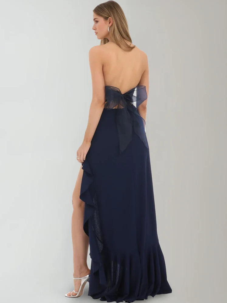 Dark navy strapless ruffle formal dress with draped back and floor-length slit.