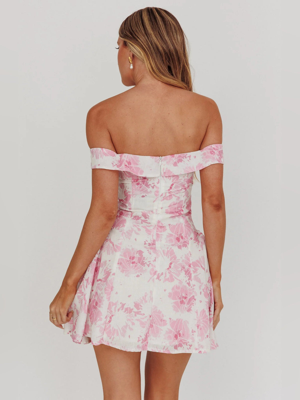 Back view of pink floral off-shoulder mini dress with fitted waist and skirt flare