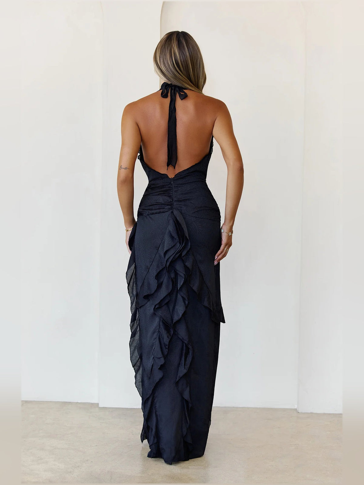 Black a-line maxi formal dress with ruffle details, full-length back view
