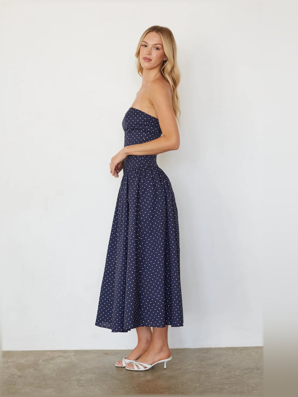 Navy strapless polka dot midi dress with fitted bodice and flared full skirt