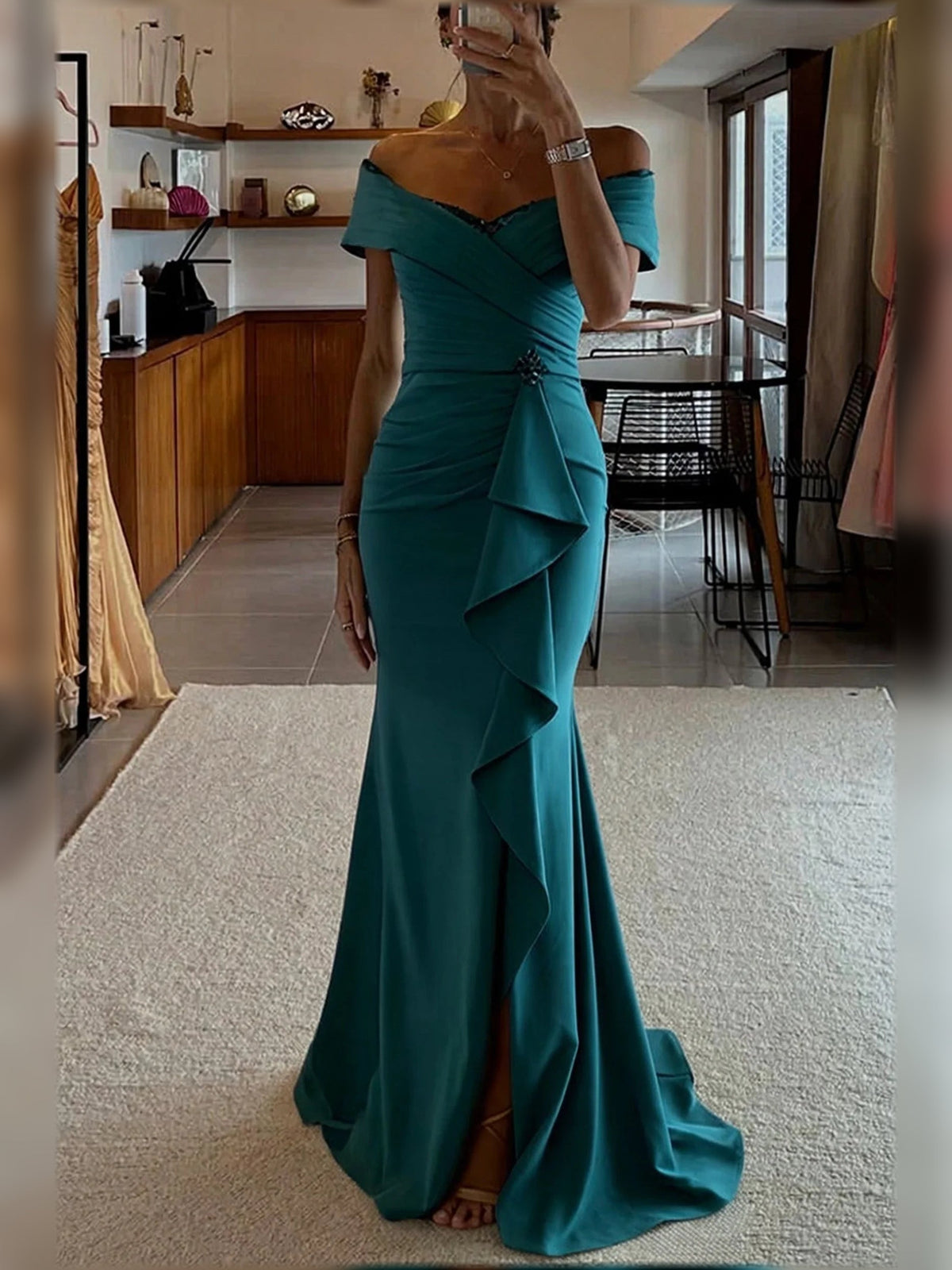 Teal off-shoulder mermaid dress with draped ruching and tiered ruffles at the slit.