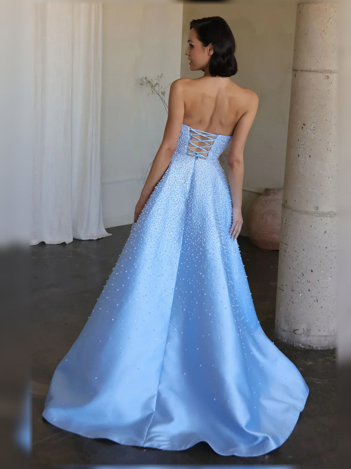 Light blue strapless beaded corset gown, back view with crossed open corset-style straps.