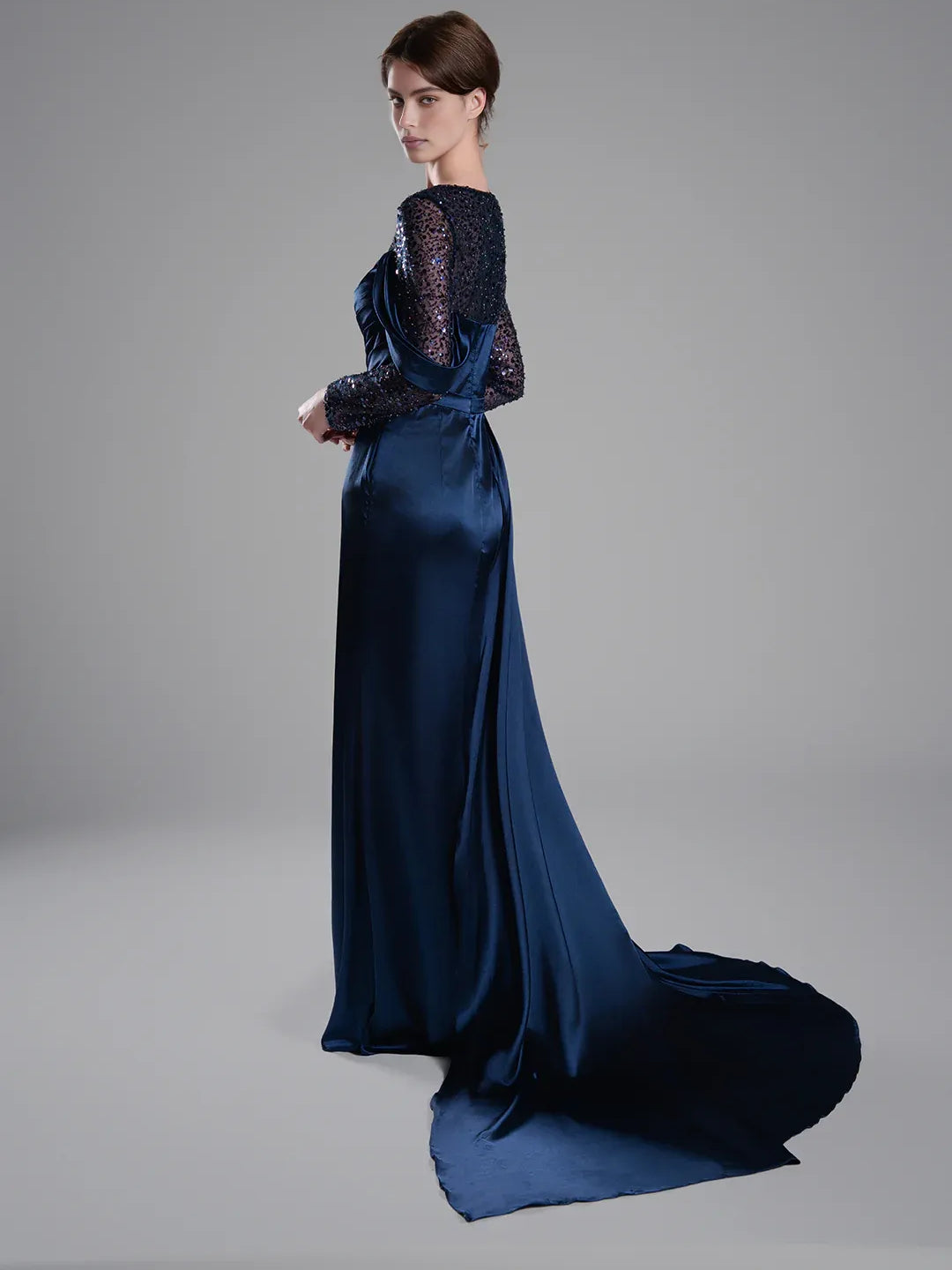 Navy blue floor-length formal dress with beaded long sleeves and flowing side drape