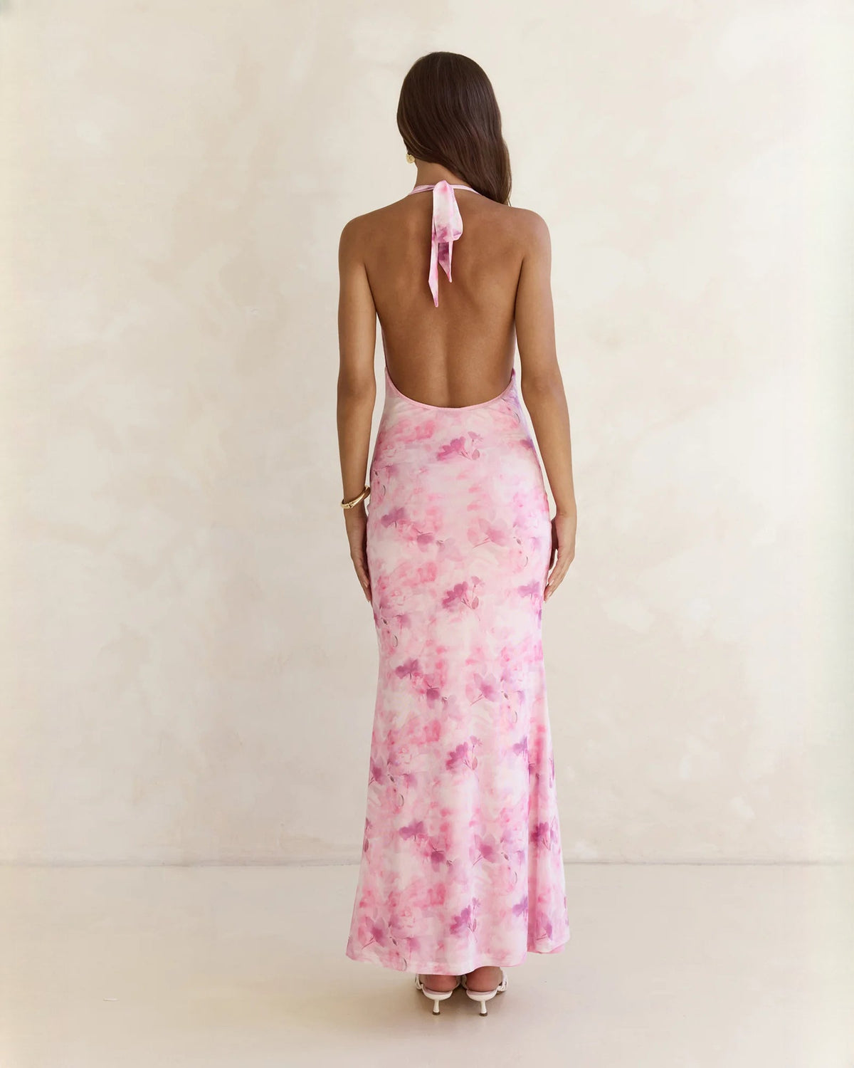 Pink floral halter neck maxi dress shown from the back with open lower back
