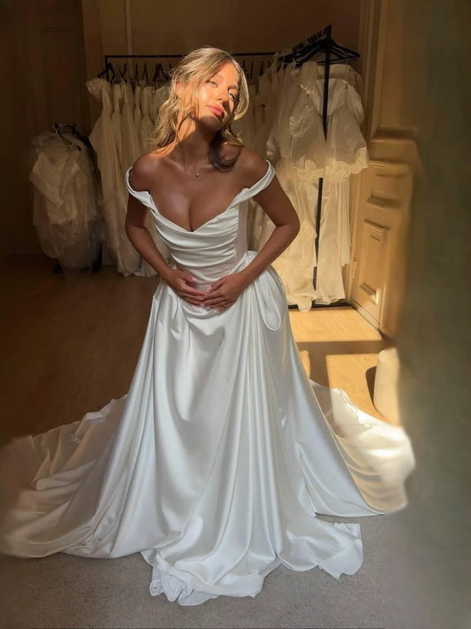 Ivory satin A-line wedding dress with draped corset, cowl neckline, and off-shoulder sleeves