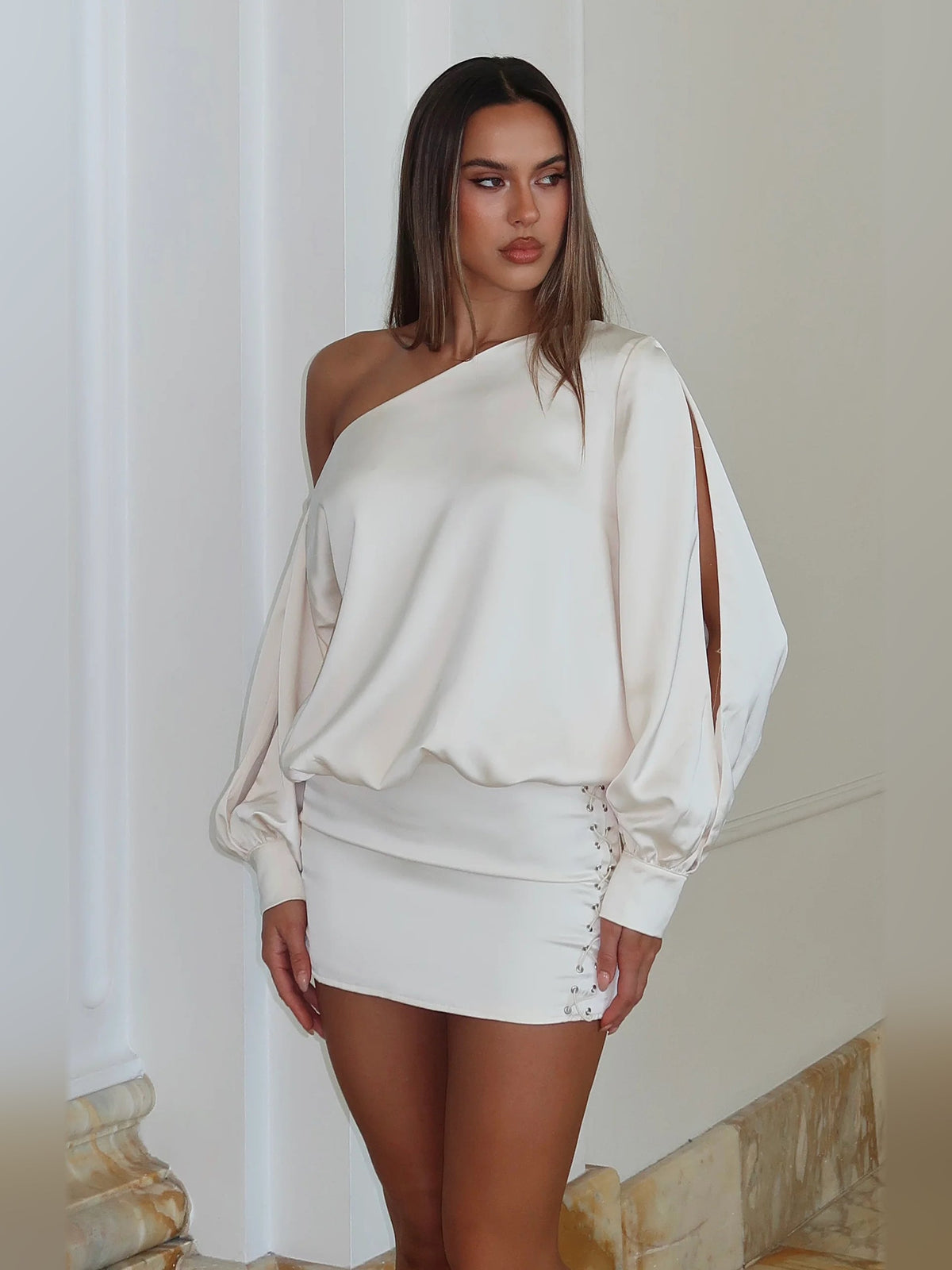 Off-white one-shoulder mini dress with draped long sleeves and ruched corset lace-up detail