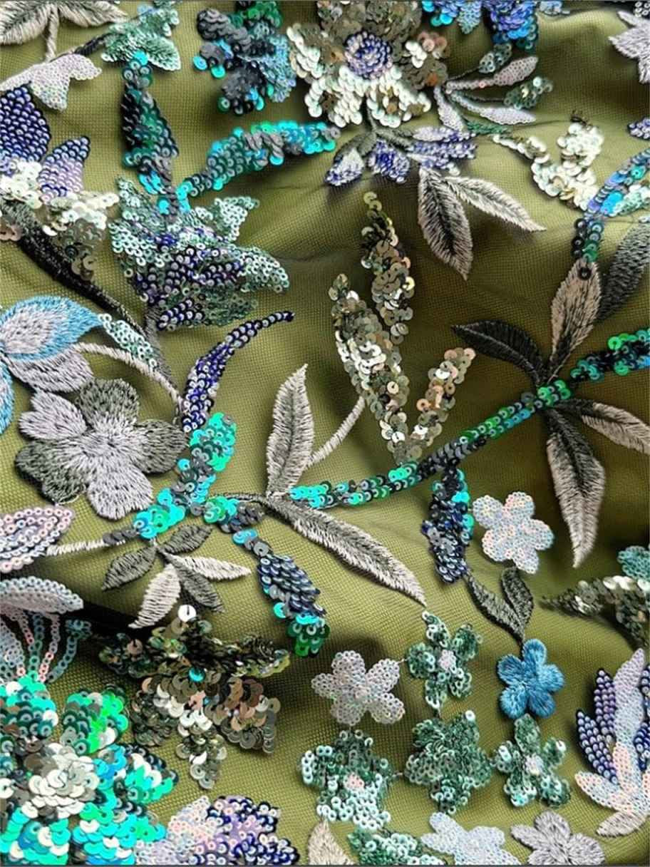 Close-up of green fabric with silver, blue, and teal floral sequin embroidery