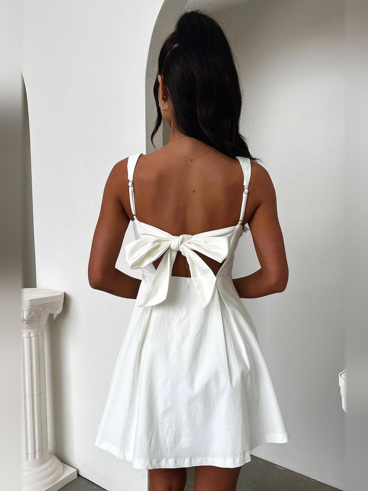 Back view of ivory A-line mini dress with square straps and large bow