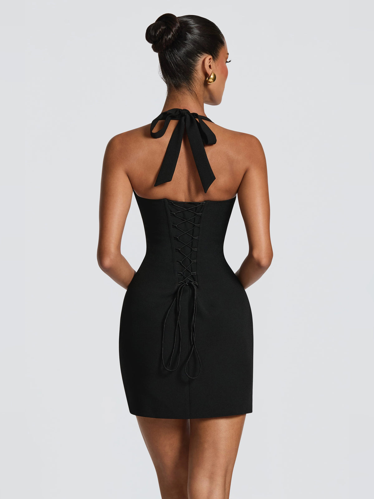 Black halter mini dress with open back, corset stitching, and bow tie at neckline