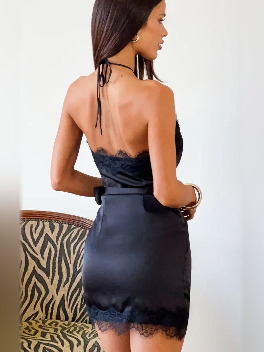 Black satin halter mini dress shown from back with tie straps and lace hem