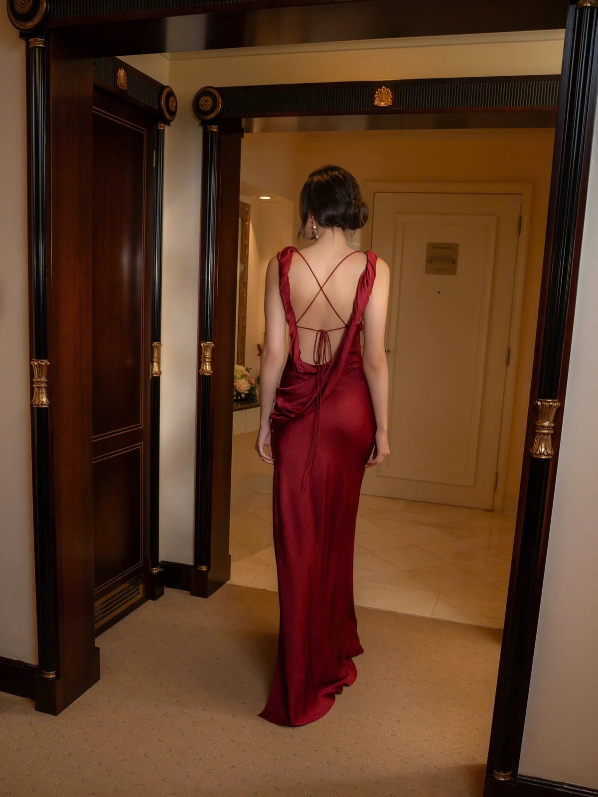 Red satin maxi dress with open back and crisscross straps, draped fabric