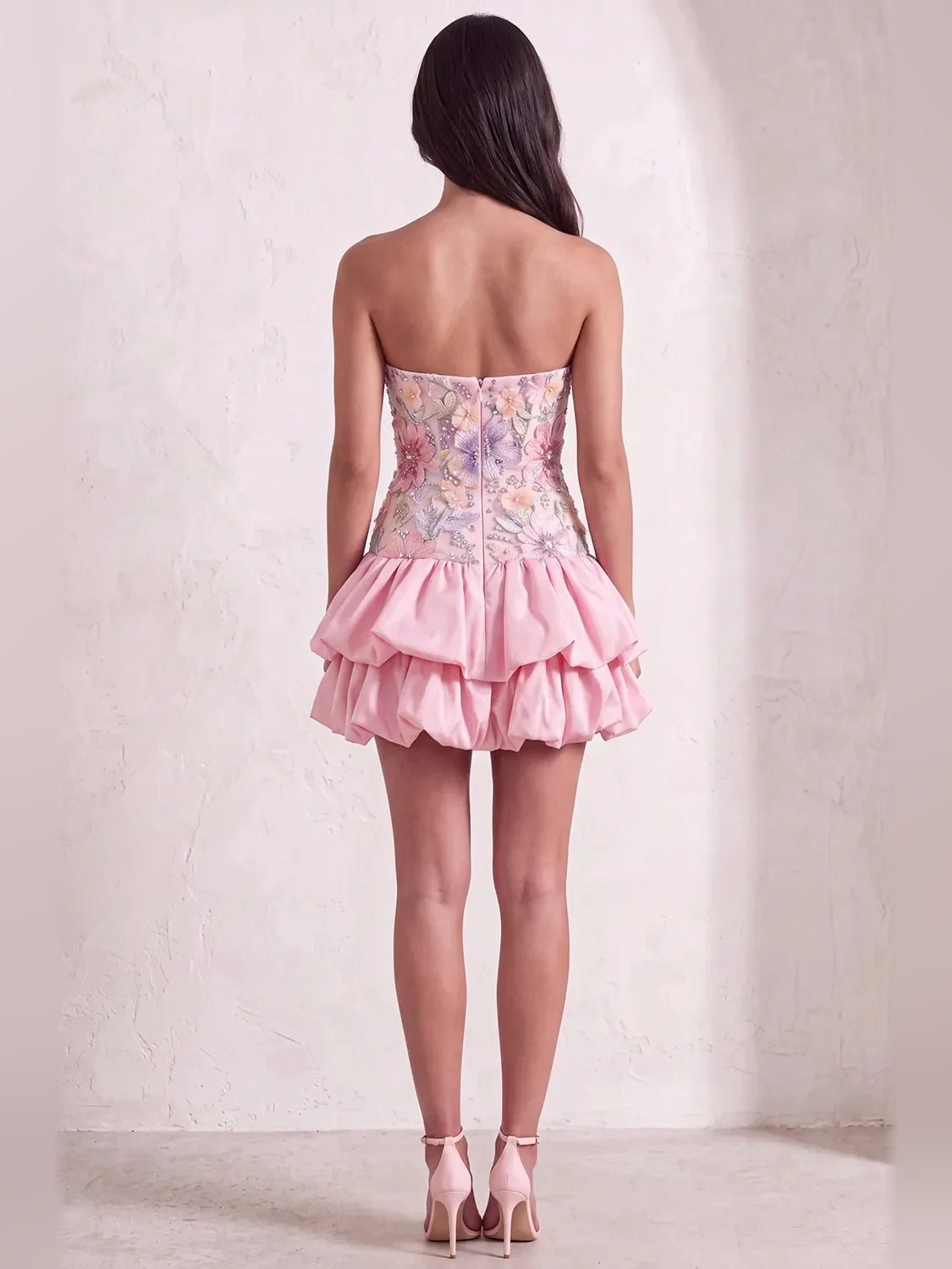 Back view of pink strapless A-line mini dress with floral applique and layered ruffles