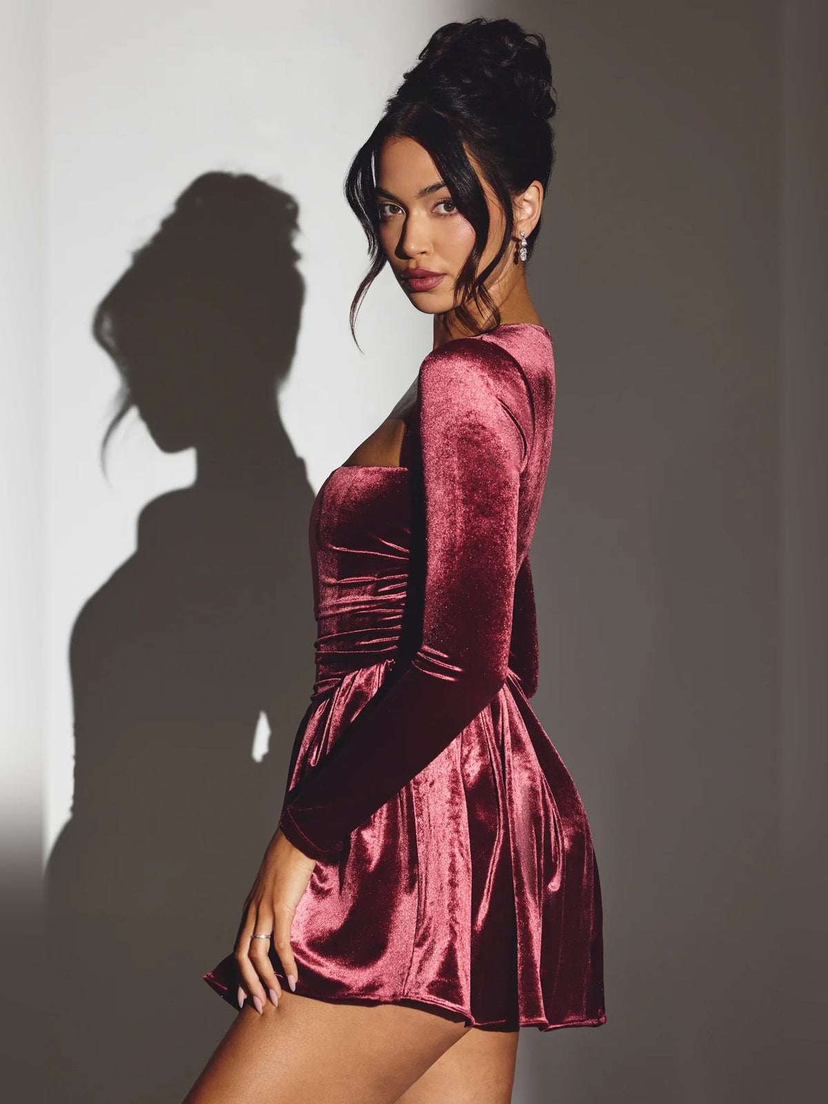 Wine velvet long-sleeve mini dress with corset ruching and flared skirt detail.