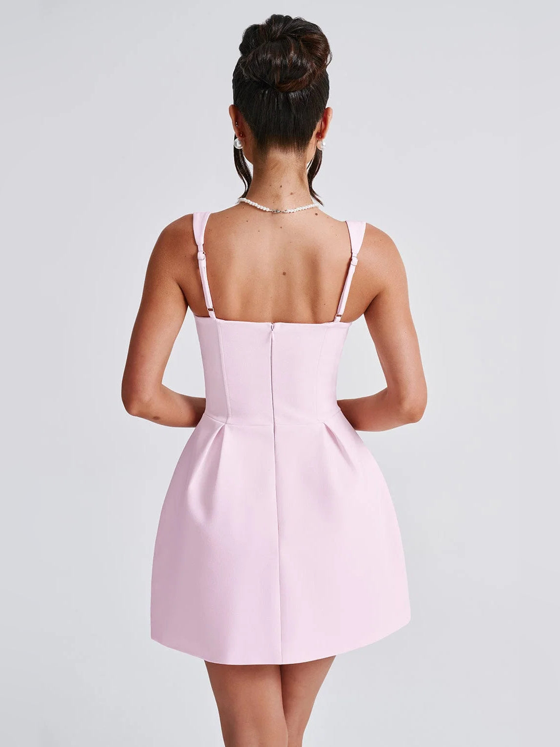 Back view of blush mini dress with spaghetti straps and a flared skirt