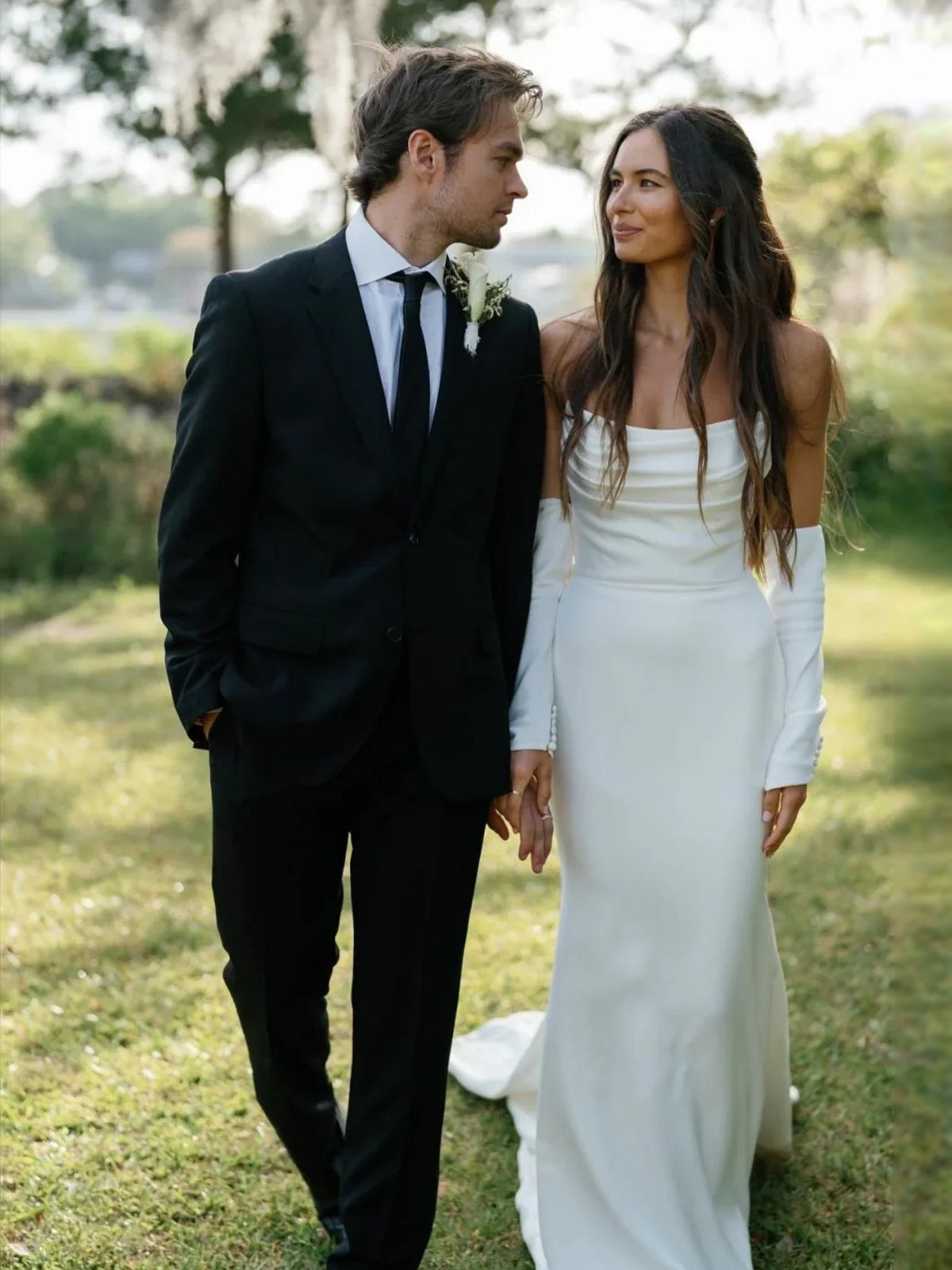White strapless mermaid wedding dress, fitted bodice and long skirt; bride standing
