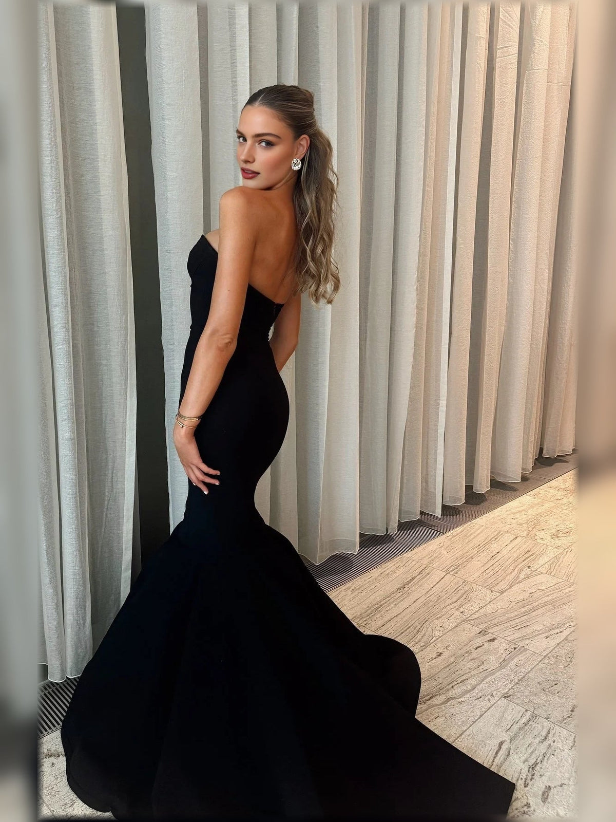 Side view black strapless formal gown with chest cutout and flared mermaid hem