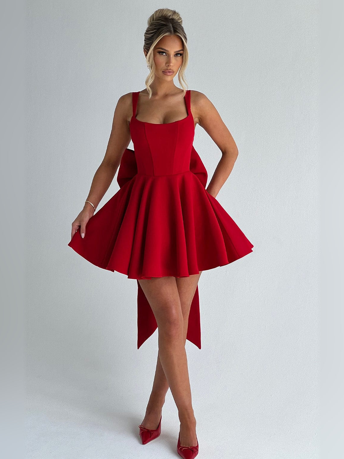Red sleeveless mini dress, fitted bodice and pleated flared skirt with asymmetrical hem tails