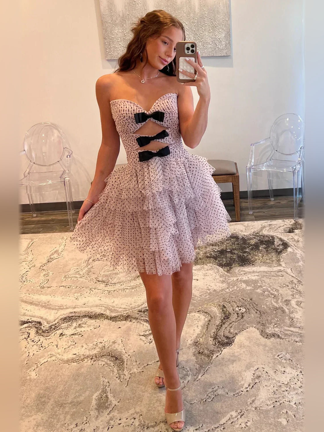 Front view pink mini tulle dress with sweetheart neckline, black bow cutouts, and flared tiers