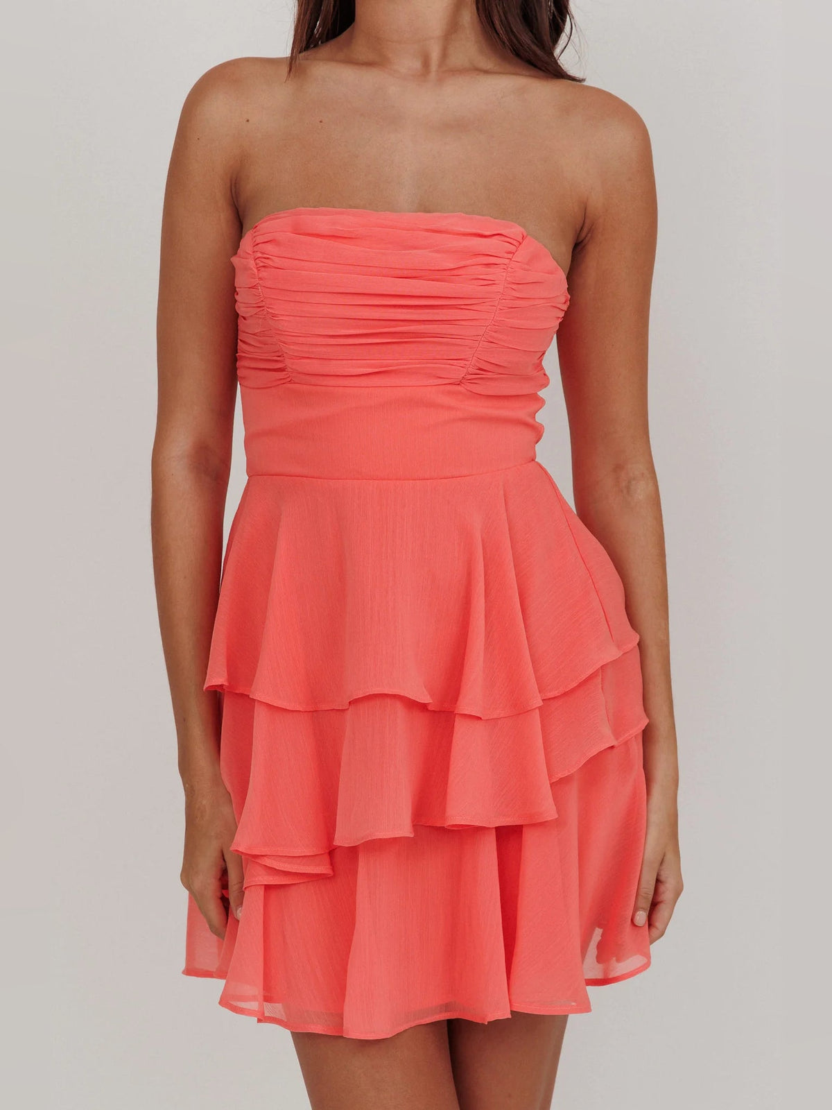 Coral strapless mini dress with gathered ruched bodice and tiered ruffle hem