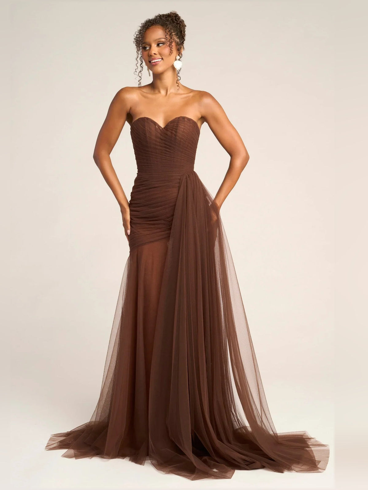 Brown strapless sweetheart draped mermaid formal dress with layered tulle skirt.