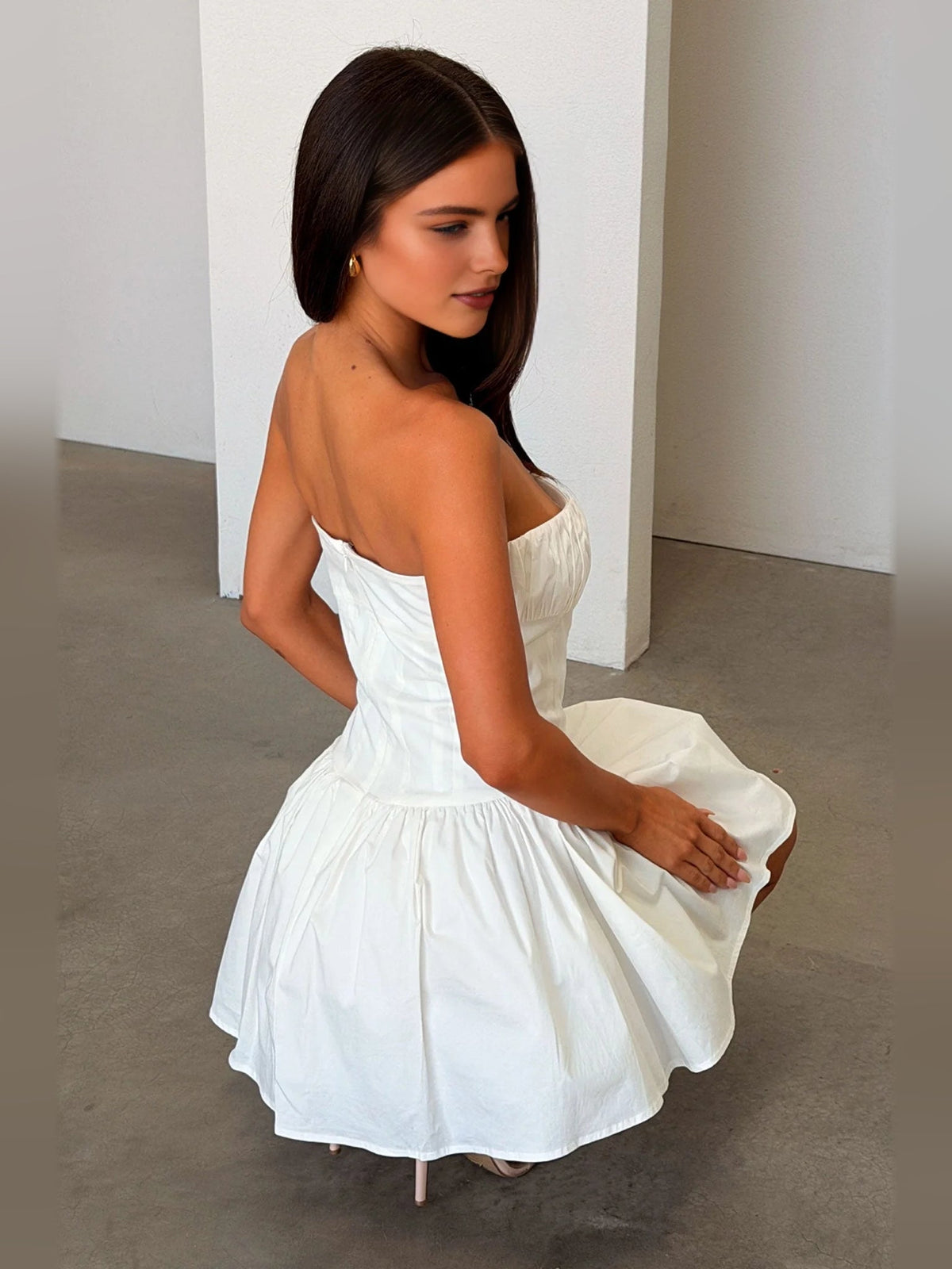 Ivory white strapless ruched corset A-line mini dress, back view with flared ruffle skirt