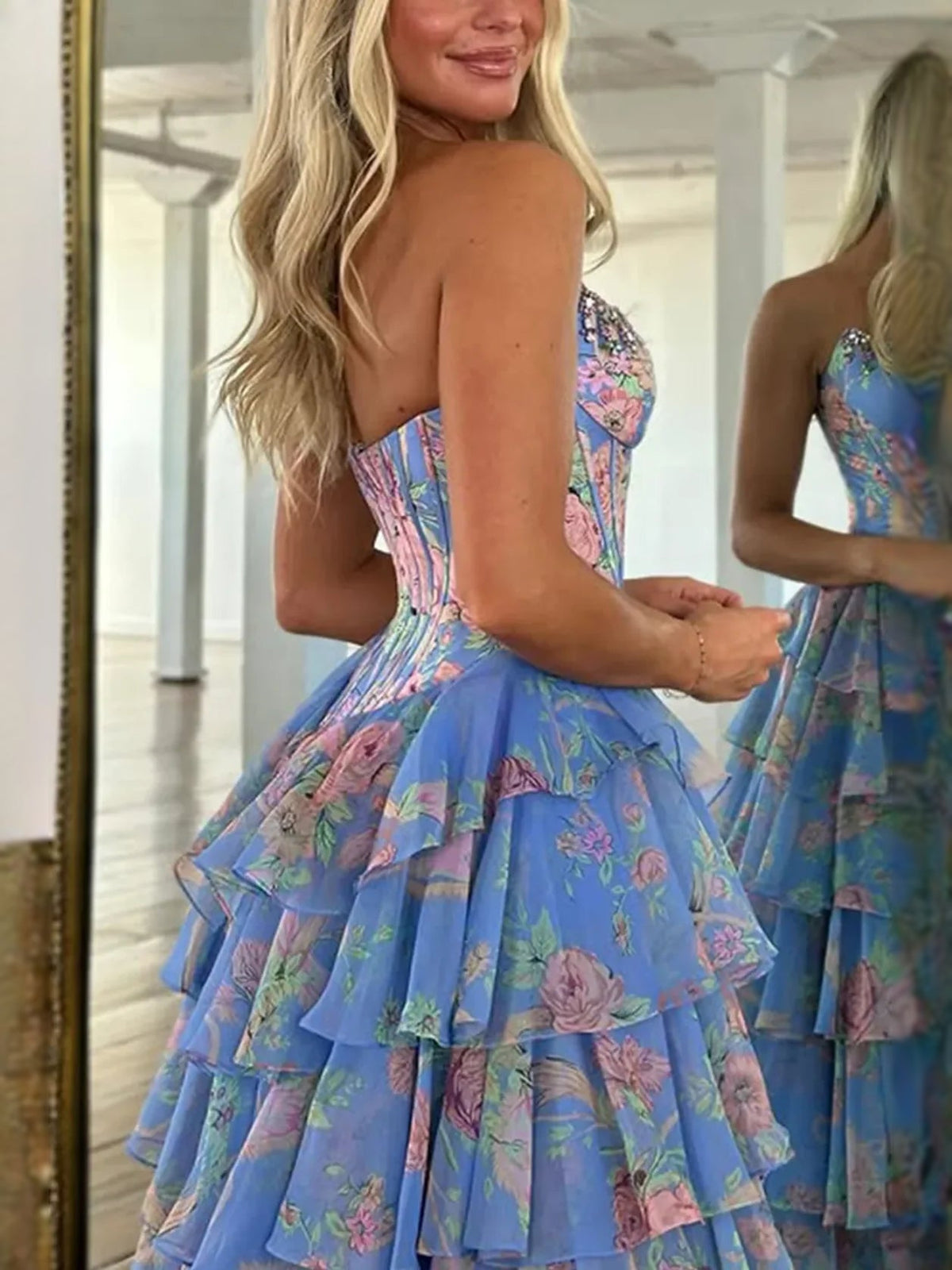Blue floral corset-style strapless prom dress with tiered ruffle skirt and front slit.