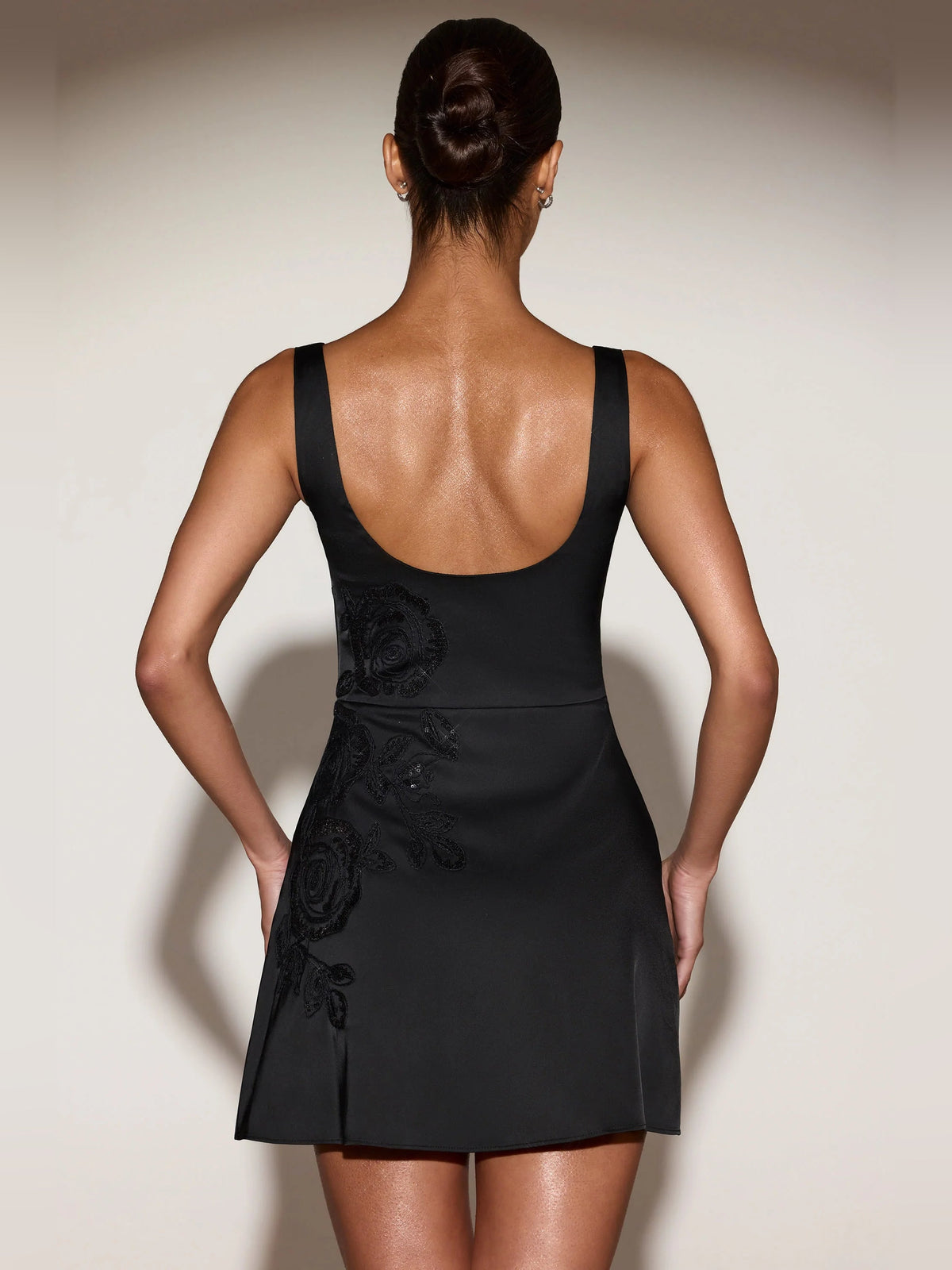 Back view of black scoop-neck A-line mini dress with floral applique