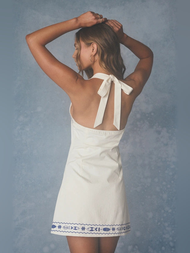 White halter mini dress with open back, two straps tied at nape, blue trim