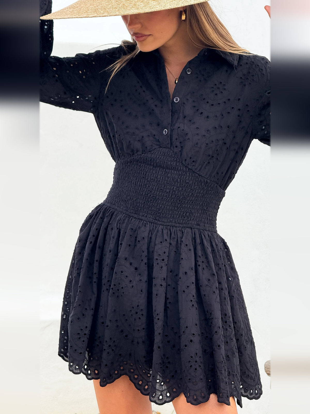 Black long-sleeve mini dress close-up: button placket, textured dots, smocked waist