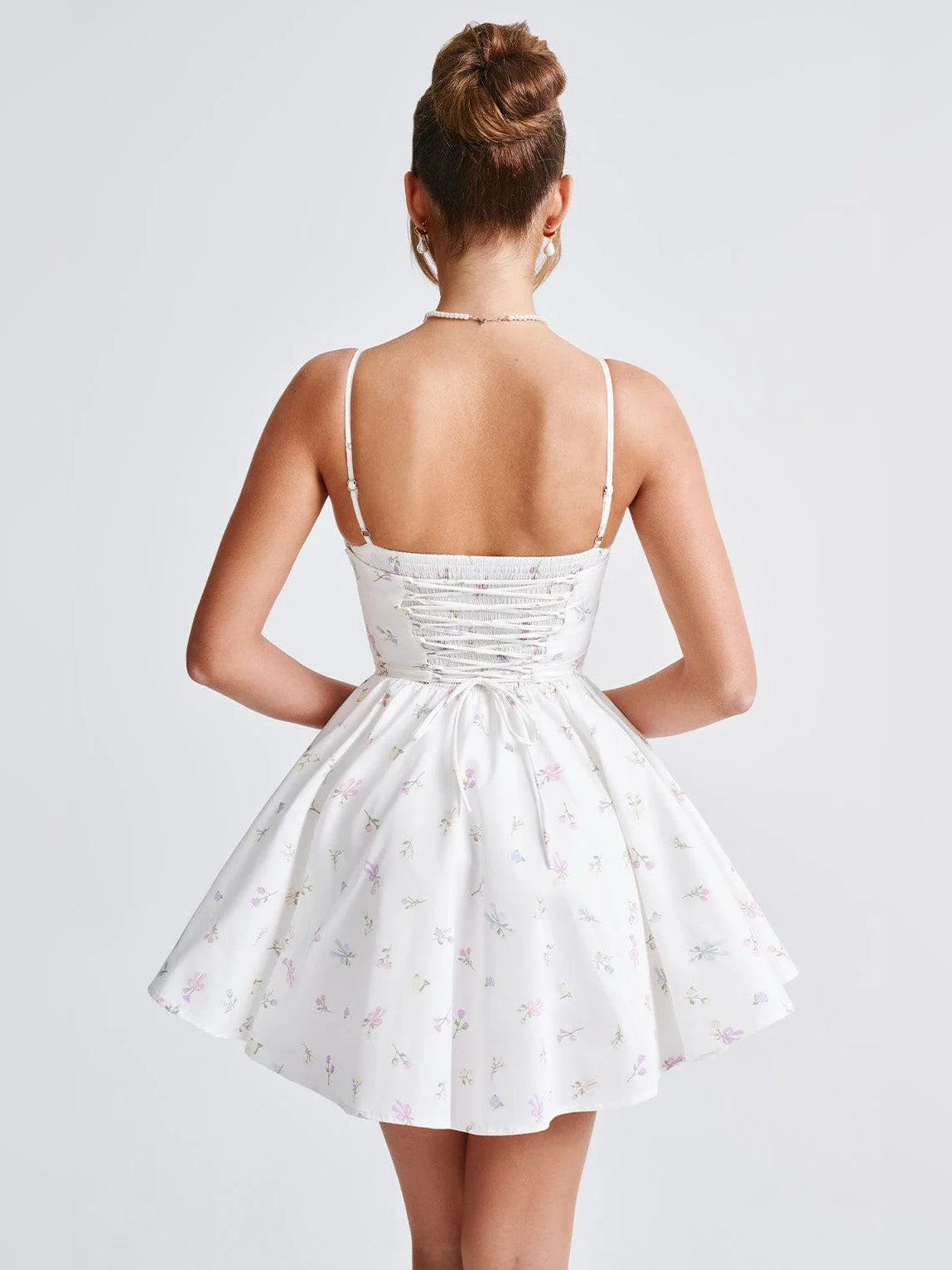 Back view of floral mini homecoming dress with gathered waist and open-strap back