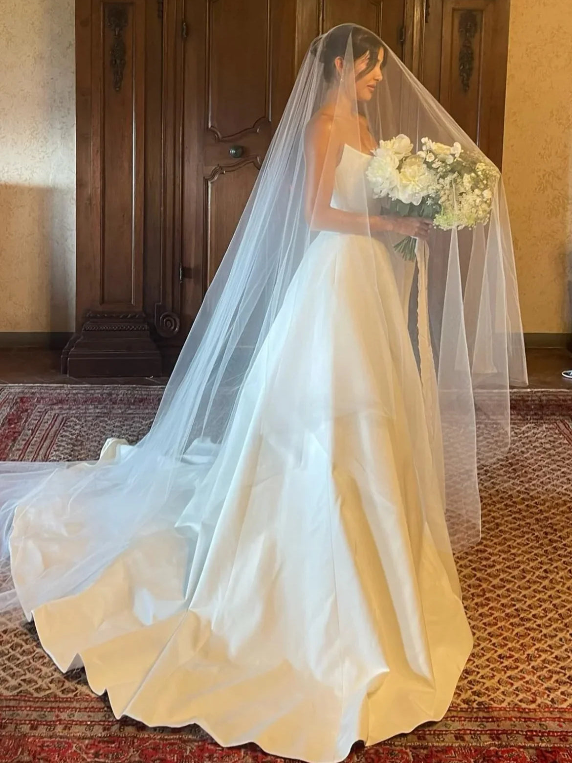 White satin A-line wedding dress with draped sweetheart bodice and long veil