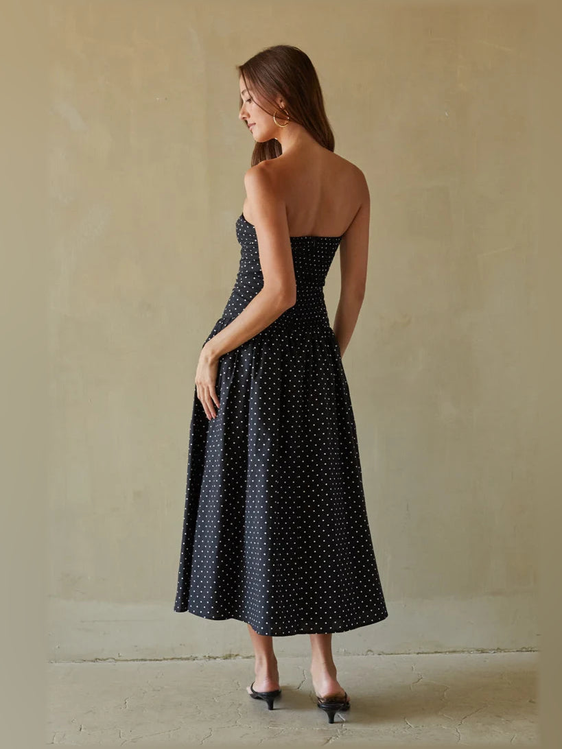 Back view of navy polka dot strapless midi dress with fitted bodice and full skirt