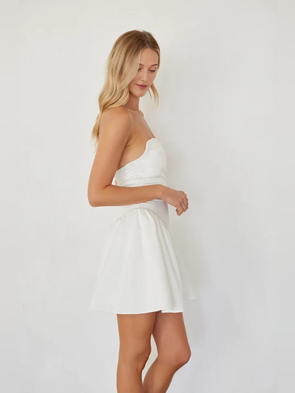 White strapless mini A-line dress with ruched bodice and flared skirt, side view