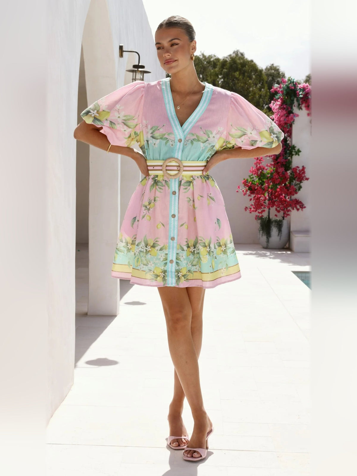 Pink floral mini dress with turquoise V-neck trim, fluttery puff sleeves, gold ring waist belt.