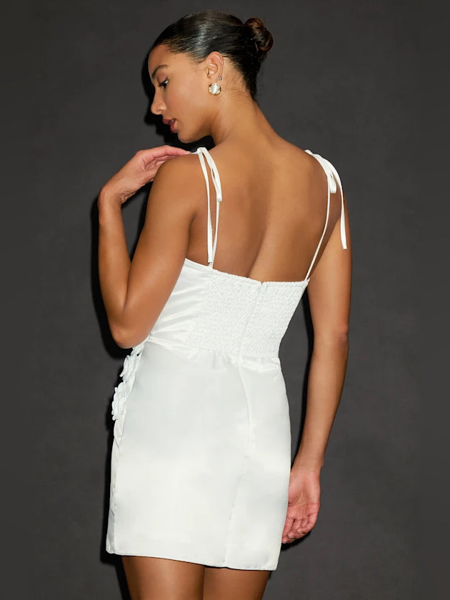 White mini satin dress from back view, open back with thin tied shoulder straps.