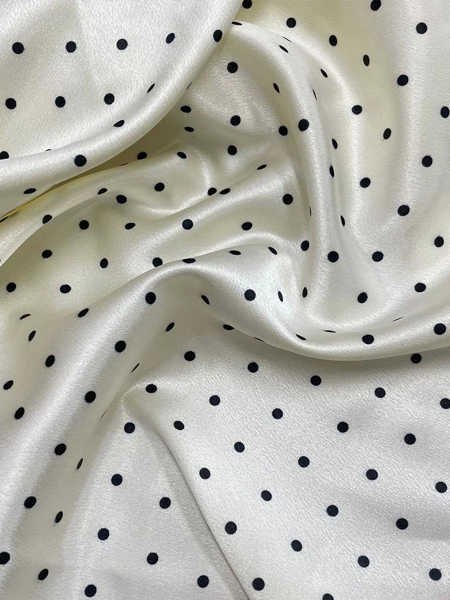 White satin fabric with black polka dot pattern, soft sheen texture